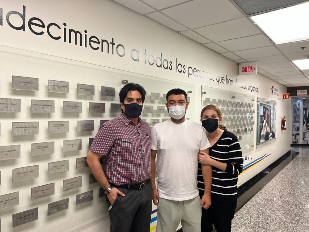 Tres de nuestros pacientes con mascarillas frente a pared de agradecimiento.