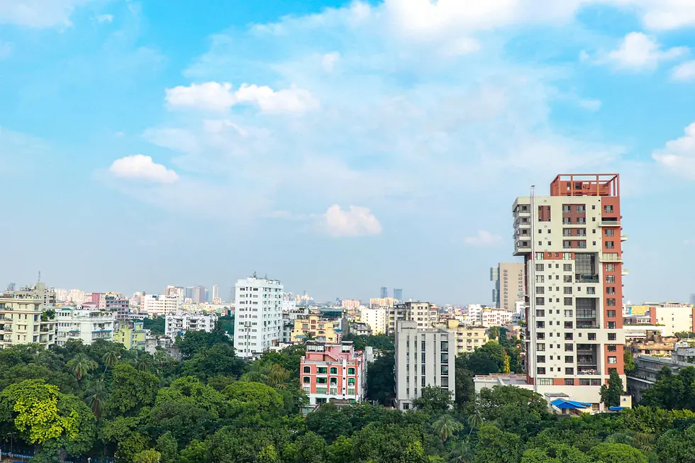 City rooftops and apartment towers among green trees under a bright sky, private jet catering at Netaji Subhas Chandra Bose International Airport (CCU / VECC), Kolkata, India