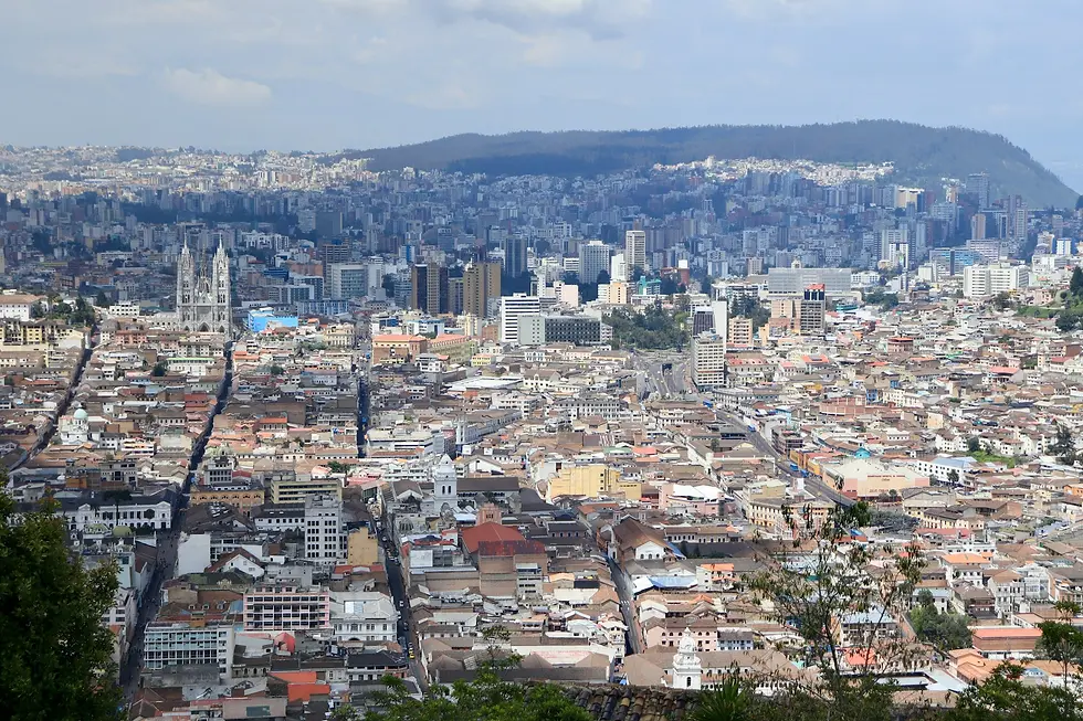 Aerial view of a dense hillside city with church towers and a hill behind, private jet catering at Eloy Alfaro International Airport (MEC / SEMT), Manta, Ecuador