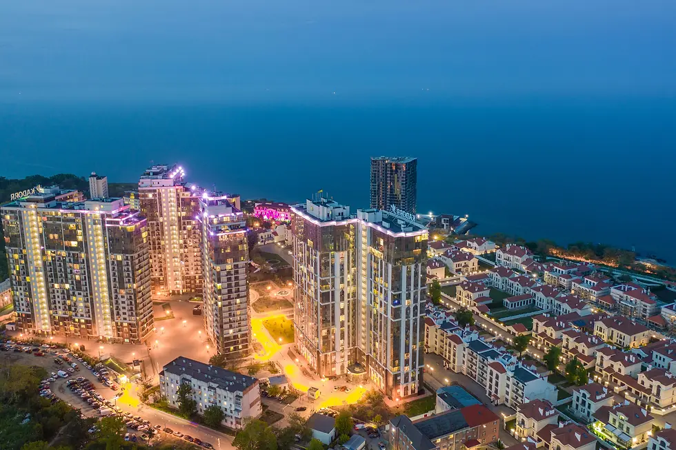Illuminated waterfront apartment towers glowing at dusk beside the sea, private jet catering at Odessa International Airport (ODS / UKOO), Odesa, Ukraine
