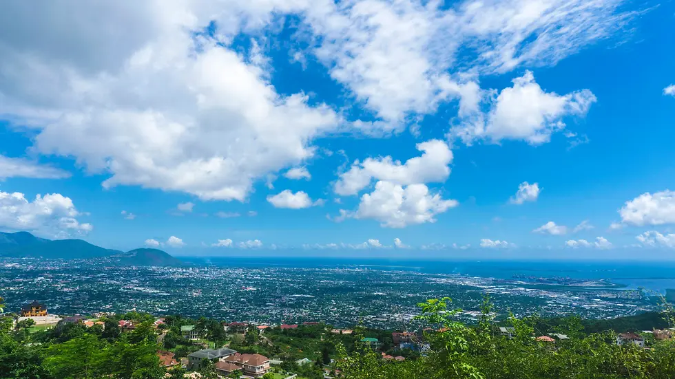 Green hillside view over a coastal city under bright white clouds, private jet catering at Norman Manley International Airport (KIN / MKJP), Kingston, Jamaica