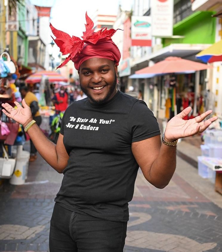 Bajan actor and social media influencer Akhnaten Burrowes wearing a vibrant read headpiece in downtown Barbados.