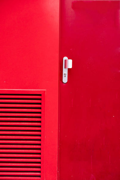 Photo minimaliste d'une porte très graphique rouge vif pour sublimer le paysage urbain banal