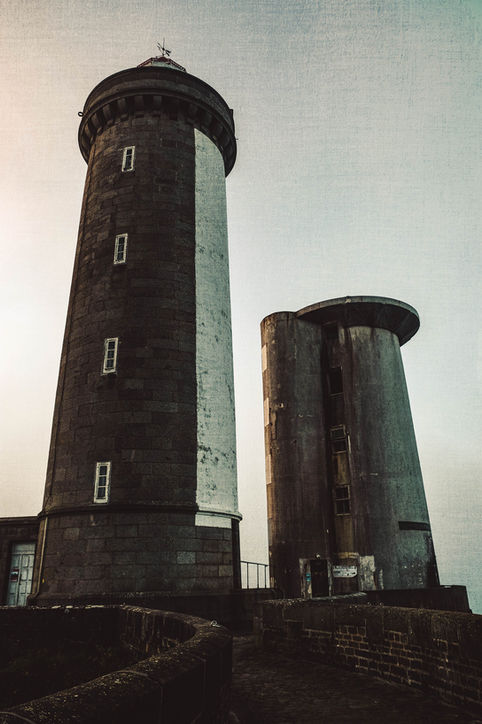 Photographie d'art montrant la tour en pierre du phare du Petit Minou à côté de la tour radar en béton brut sous un ciel blanc par Jean-François Naturel.