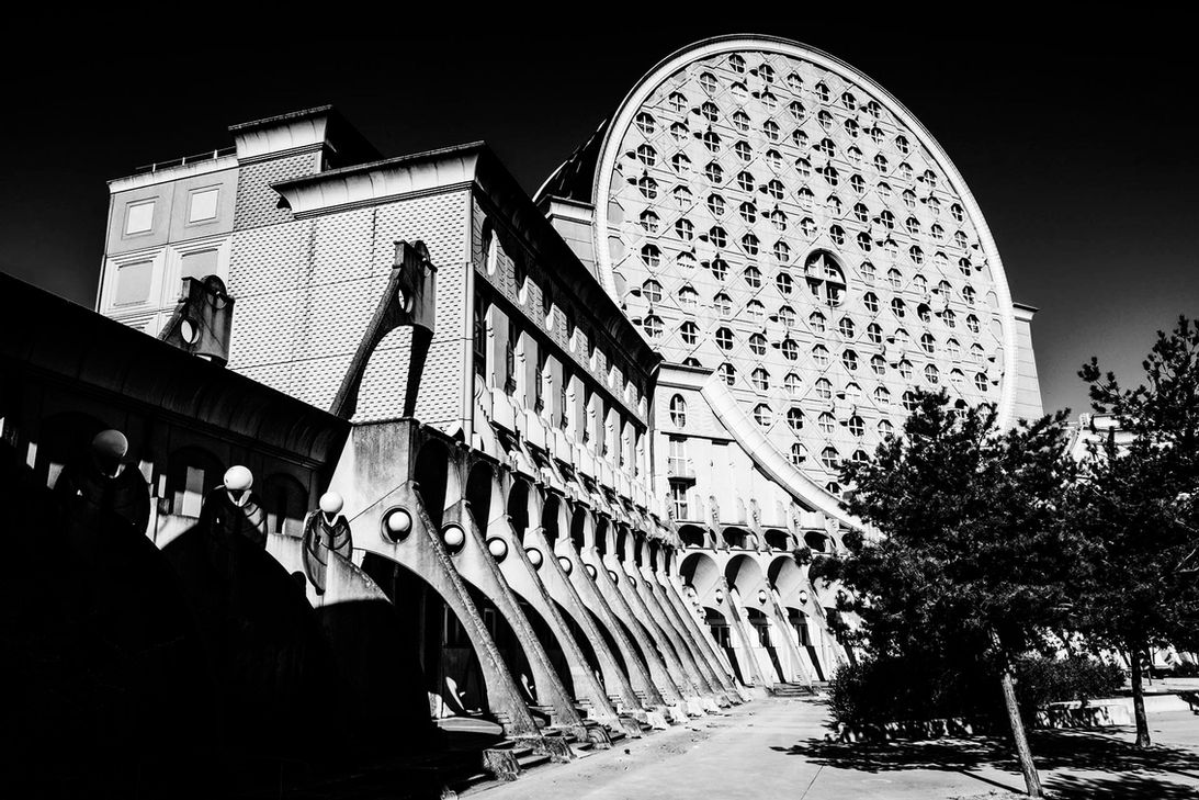 Photographie d'art en noir et blanc montrant l'enfilade des arches de béton menant au grand disque circulaire des Camemberts de Noisy-le-Grand par Jean-François Naturel.