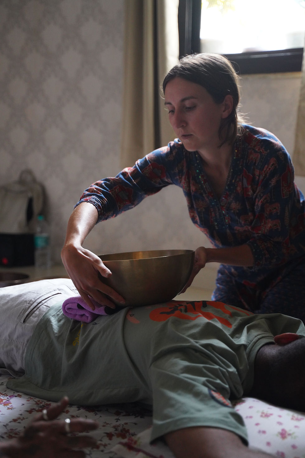 A singing bowl played near the solar plexus to balance the Manipura chakra during a sound healing session in Rishikesh.