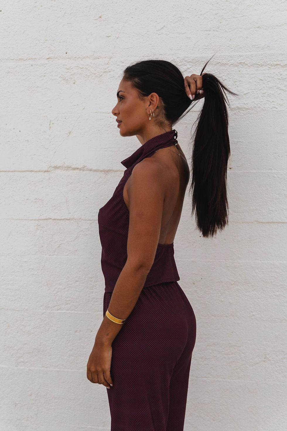Miniatura: Mulher perfil, vestindo um conjunto vermelho, cabelo preso, Melanina, contra parede branca.