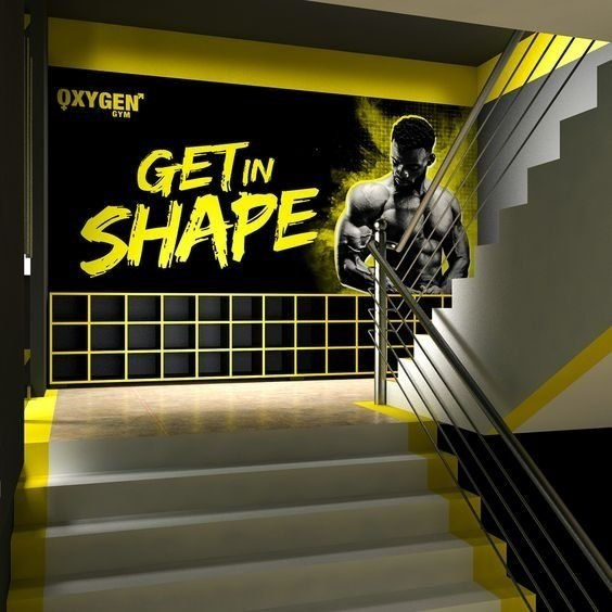 درج داخلي يؤدي إلى جدار كبير يحتوي على صورة بالأبيض والأسود لرجل رياضي. عبارة "GET IN SHAPE" باللون الأصفر على الجدار.