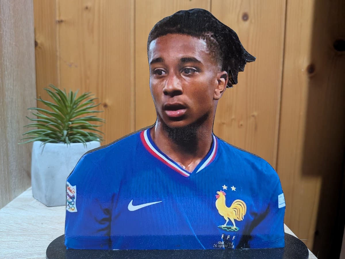 Figurine en bois faite main de Michael Olise avec le maillot bleu de l'Équipe de France de football, posée sur un