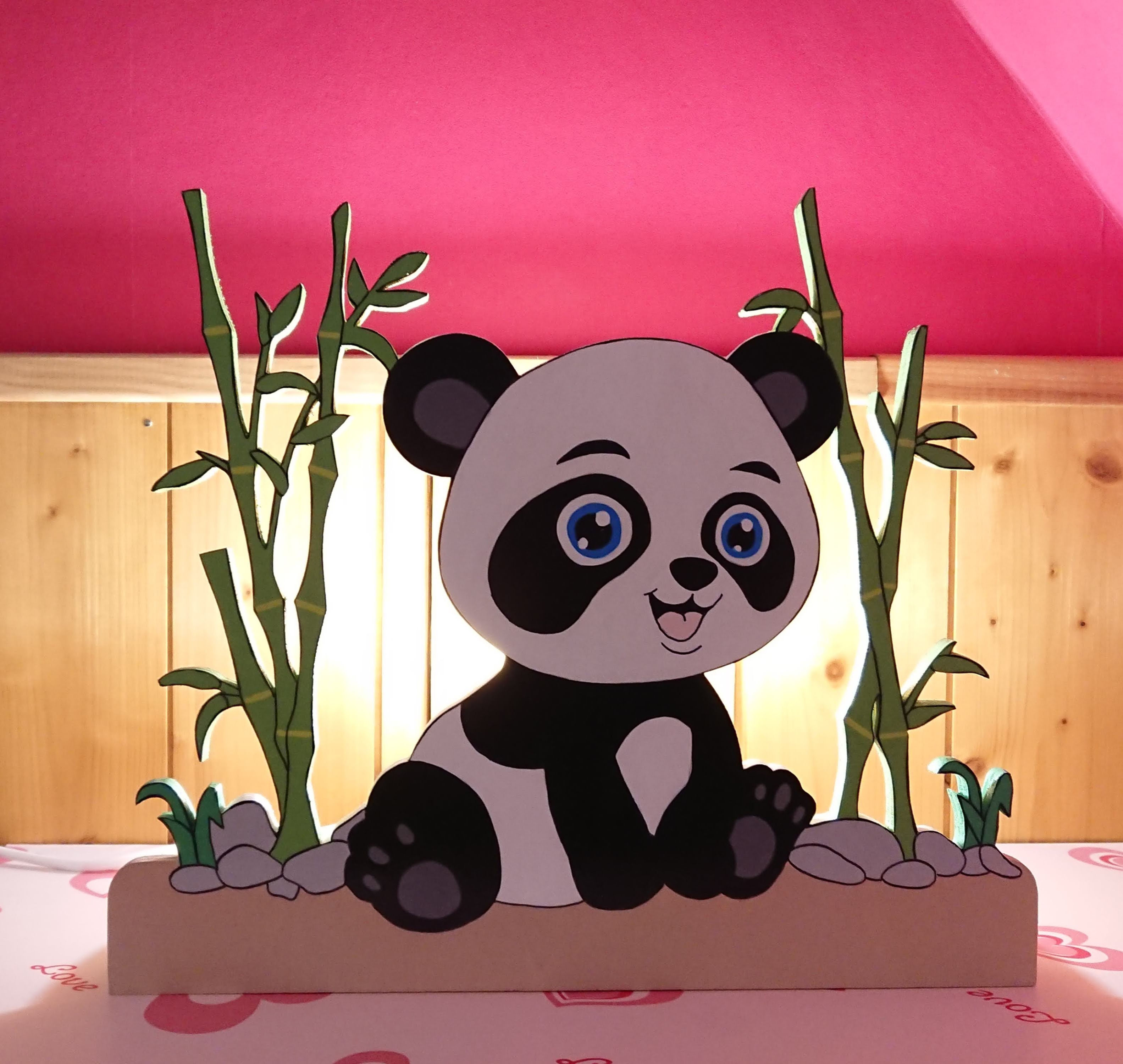 lampe de chevet en bois décorée avec un panda et des roseaux de chaque côté vue allumée