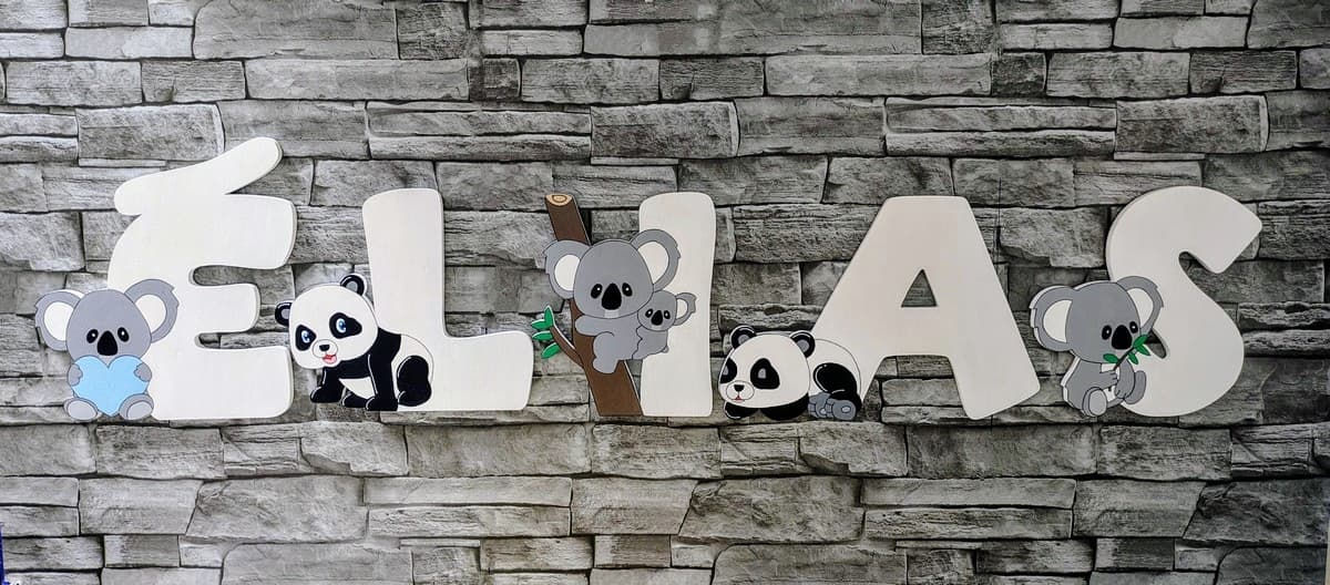 Lettres en bois décorées du prénom ELIAS avec des motifs de koalas et pandas alternés posées sur un mur gris