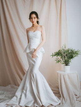 美女身穿白色婚纱，优雅地站在背景前。莯沐婚紗｜INWHITE BRIDAL COUTURE
