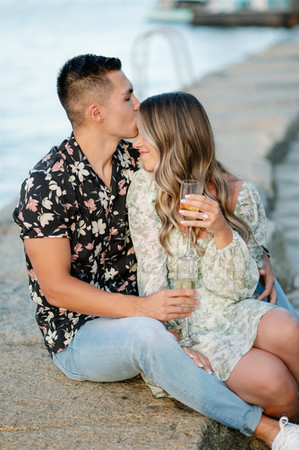 couple snuggling next to boston harbor with champagne