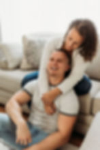in home engagement session girls arms around guy's shoulders from behind