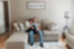 in home engagement session couple sits on couch cuddly
