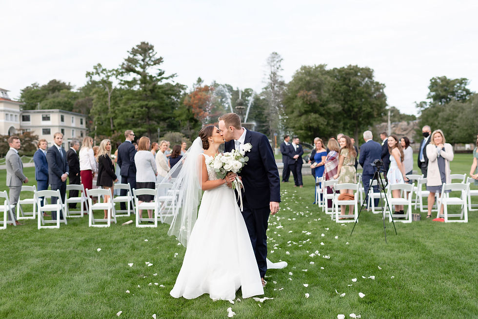 couple kisses at end of aisle with all of their guests behind them