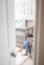 in home newborn session through the door photo with only the mom's legs showing as she is breast feeding