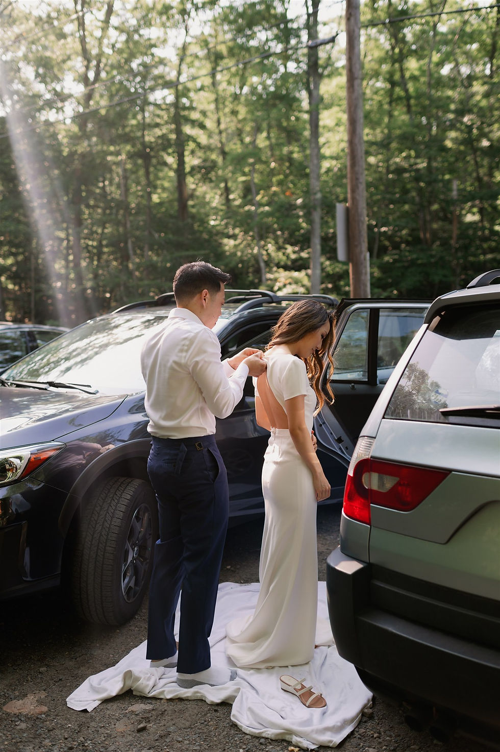 groom helping bride with the buttons on her wedding dress