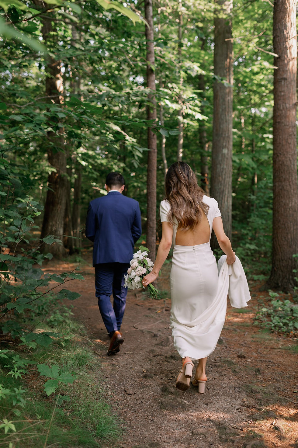 bride and groom hiking along trail at rafes chasm trailhead to get search for their elopement location