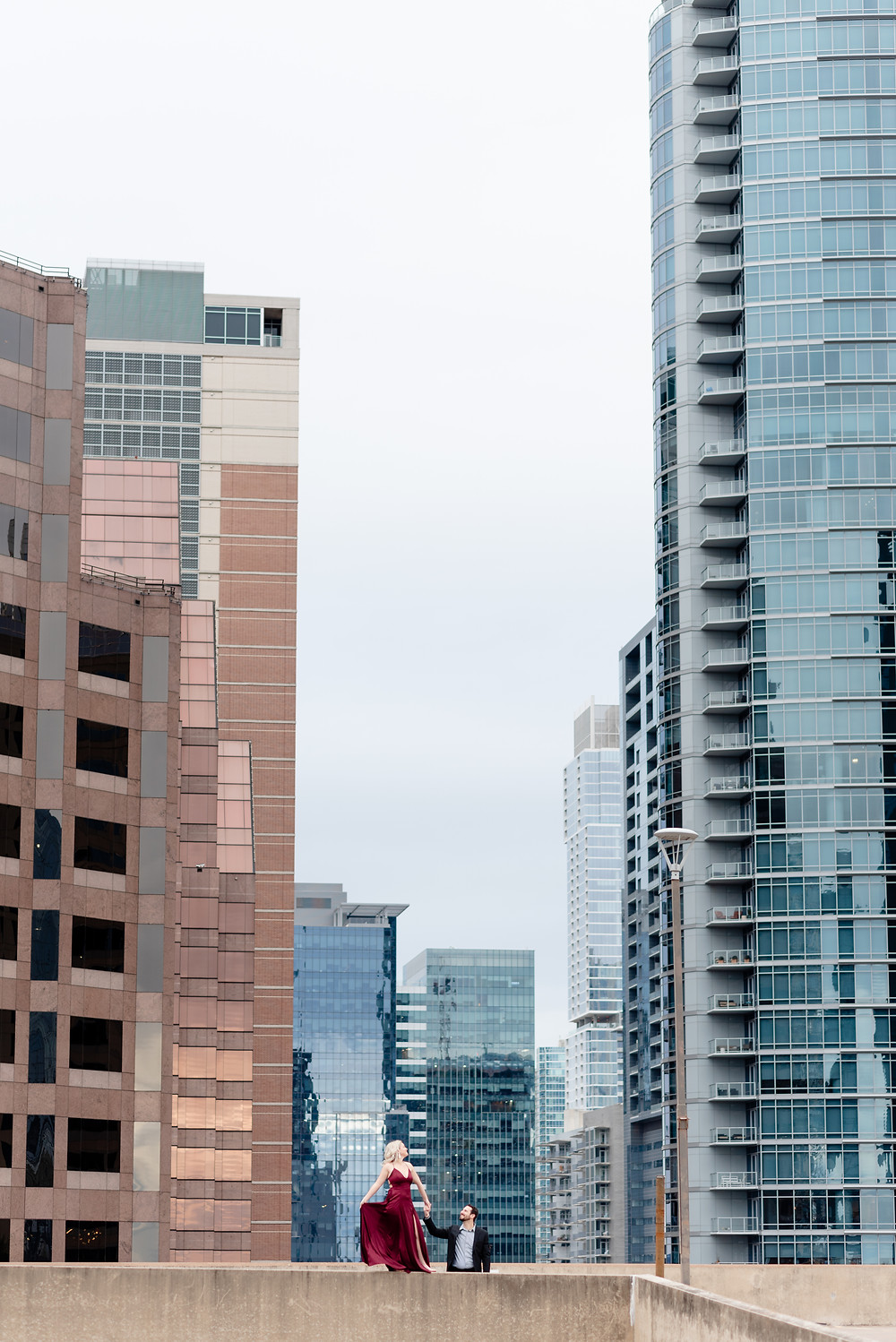 a couple in formal attire on the roof of a parking garage in downtown austin texas for their engagement photos