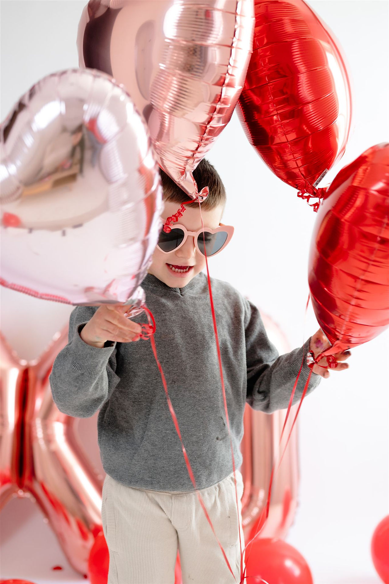 little boy playing with heart balloons