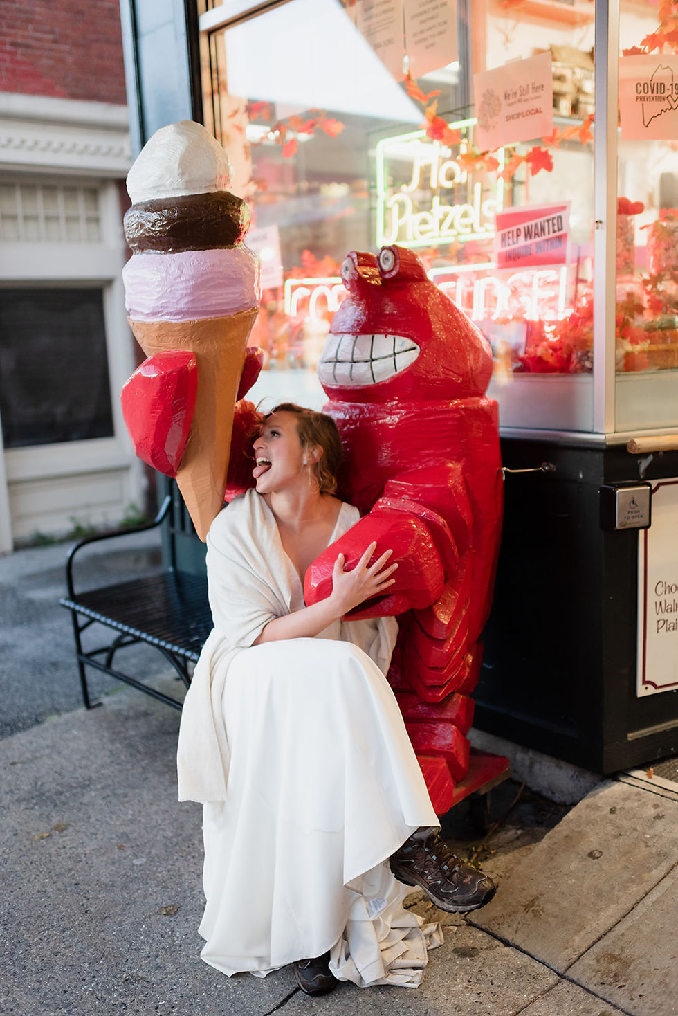 bride sitting on lobster holding ice cream cone outside of Ben & Bill's Chocolate Emporium in Bar Harbor, Maine