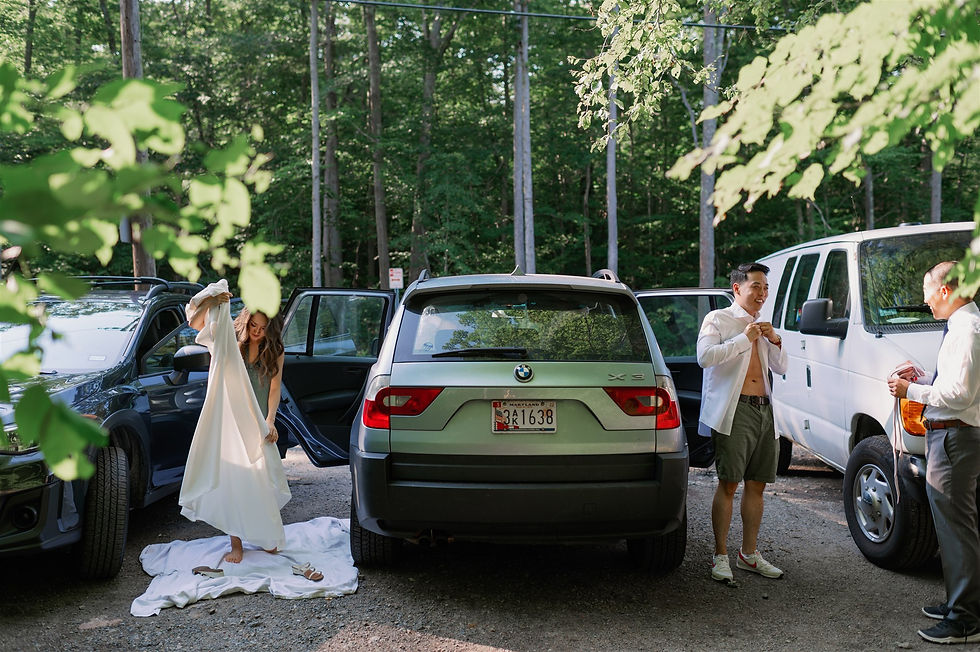 couple getting into their wedding attire outside on either side of the car