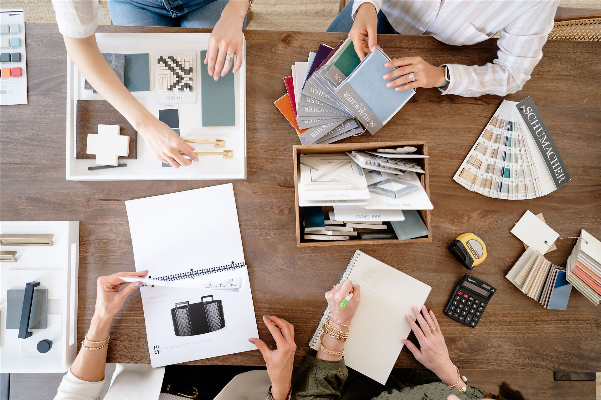 overhead shot of four women working together on different home samples and notebooks
