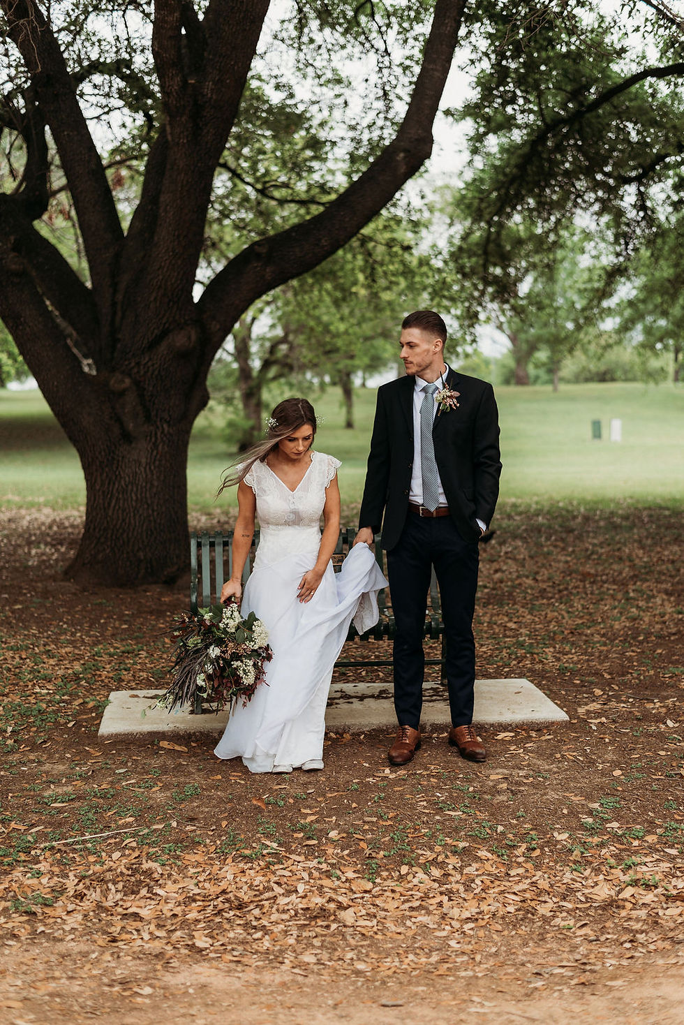 bride and groom stand side by side looking in opposite ways. they are standing in front of a bench at festival beach near lady bird lake during their Austin elopement
