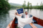 newlyweds on a boat to travel to wedding reception at squam lake inn in holderness, nh