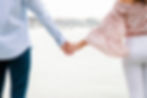 couple holding hands to show engagement ring with the boston harbor in the background