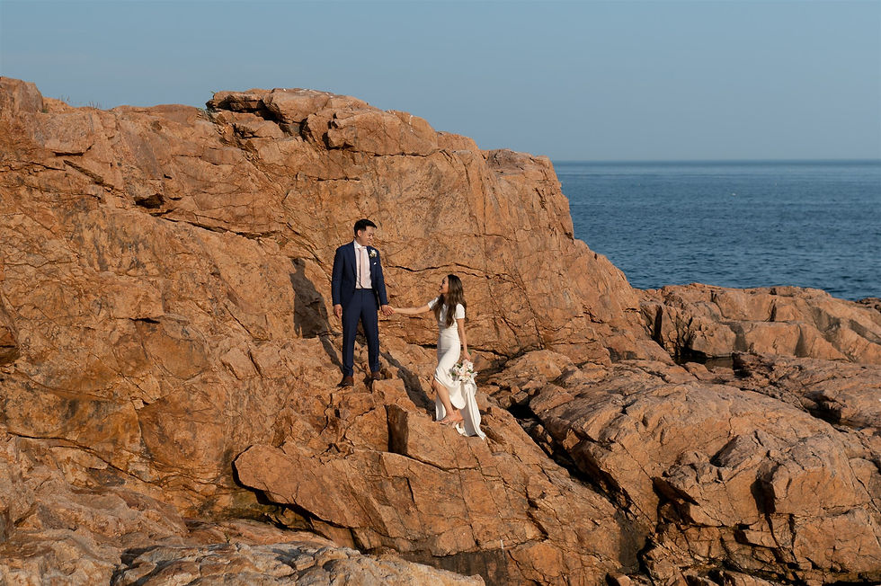 Rafes Chasm elopement couple scrambling on orange rocks along the coast of Gloucester
