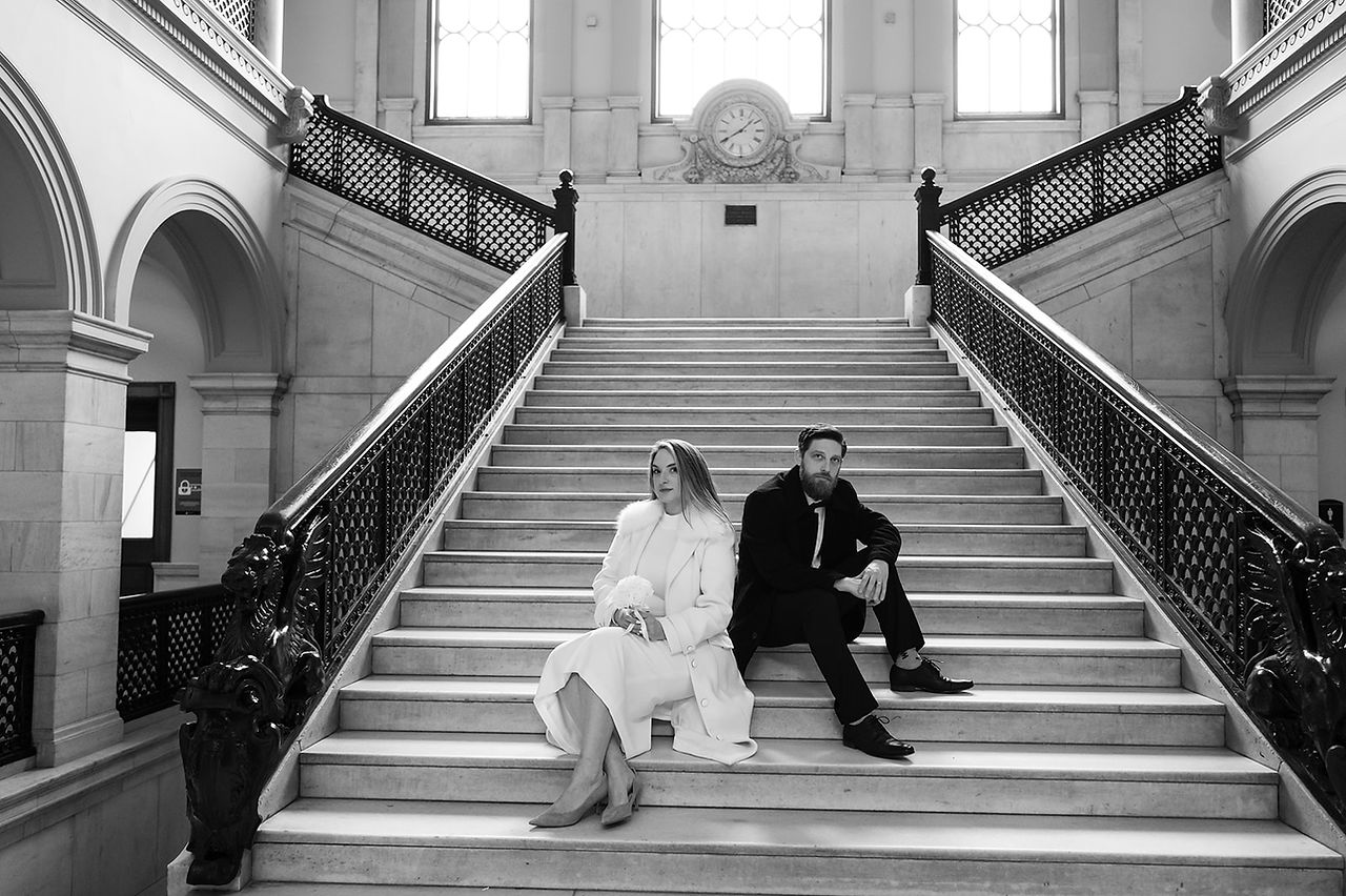 black and white editorial photo of wedding couple sitting on steps of grand staircase at worcester city hall