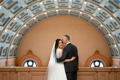 couple facing away from camera with groom kissing bride's forehead