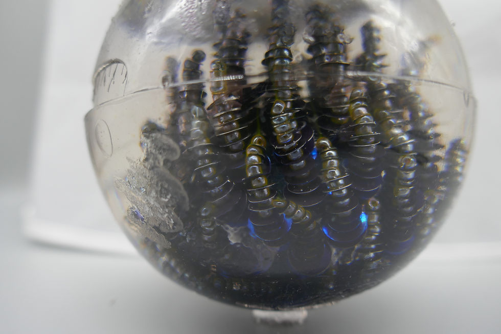 A resin sphere with embedded sequins that have melted and lost their colour