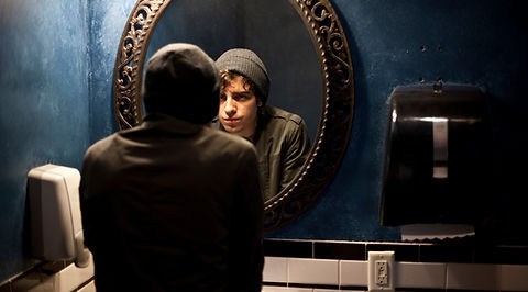person looking into the mirror looking sad.