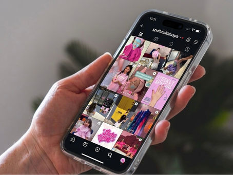 Close-up view of a person holding a smartphone displaying a colorful social media feed with various marketing images.