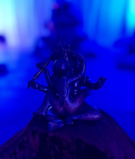 Statue de Yab-Yum du Tantra bouddhiste, avec des hommes gay pratiquant une posture tantrique (vague tantrique) en arrière-plan