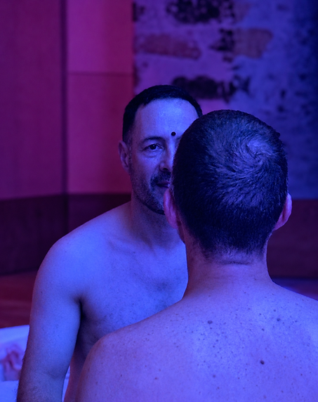 Deux hommes assis face à face échangent un regard lors d’une pratique de présence de Tantra entre hommes.