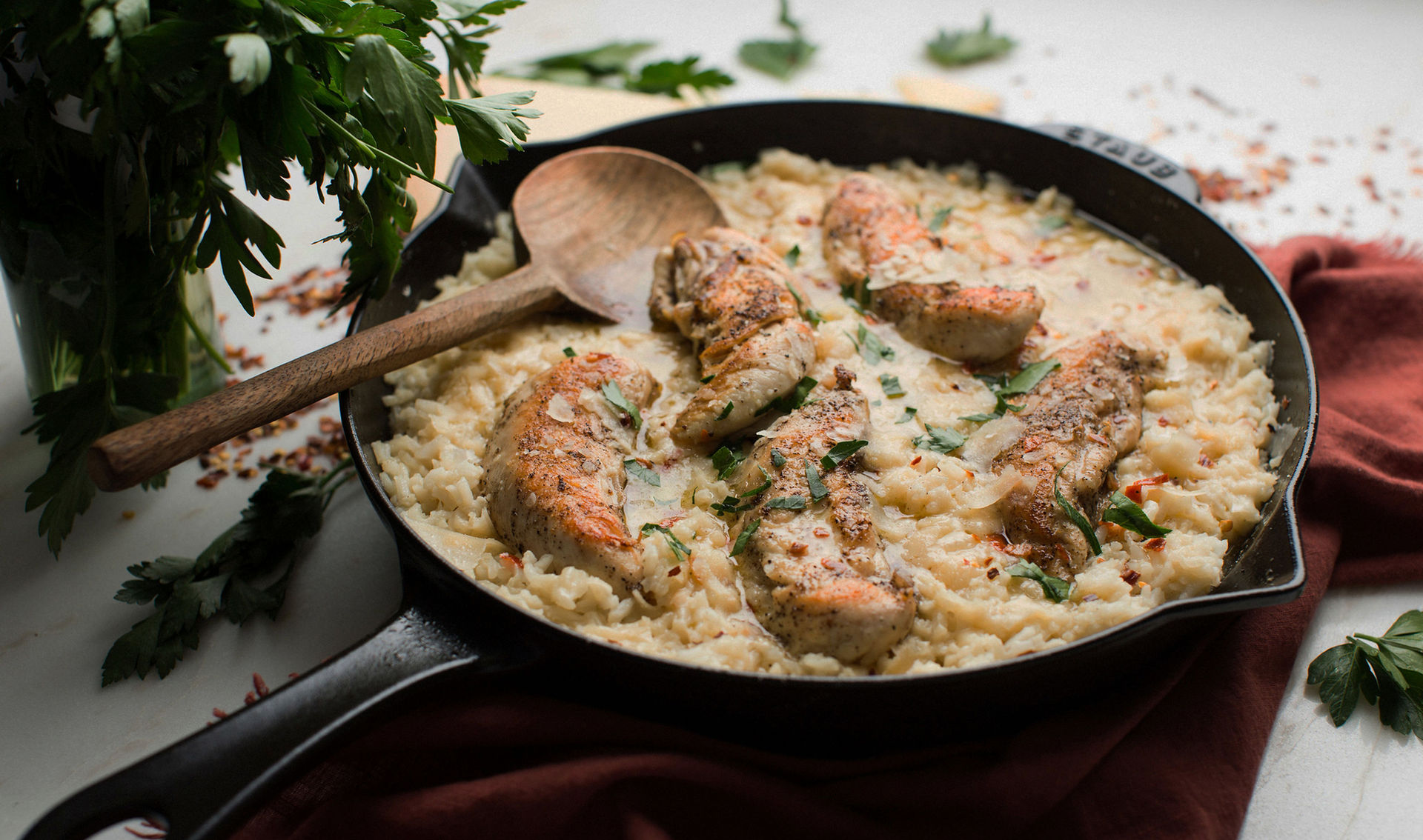 Creamy chicken and rice in a skillet with a wooden spoon