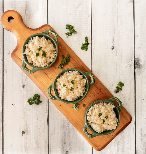 Buttery parmesan rice served in small portions on a wooden board.