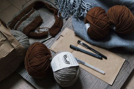 Creative workspace with yarn, knitting needles, and drawing tools on a wooden table