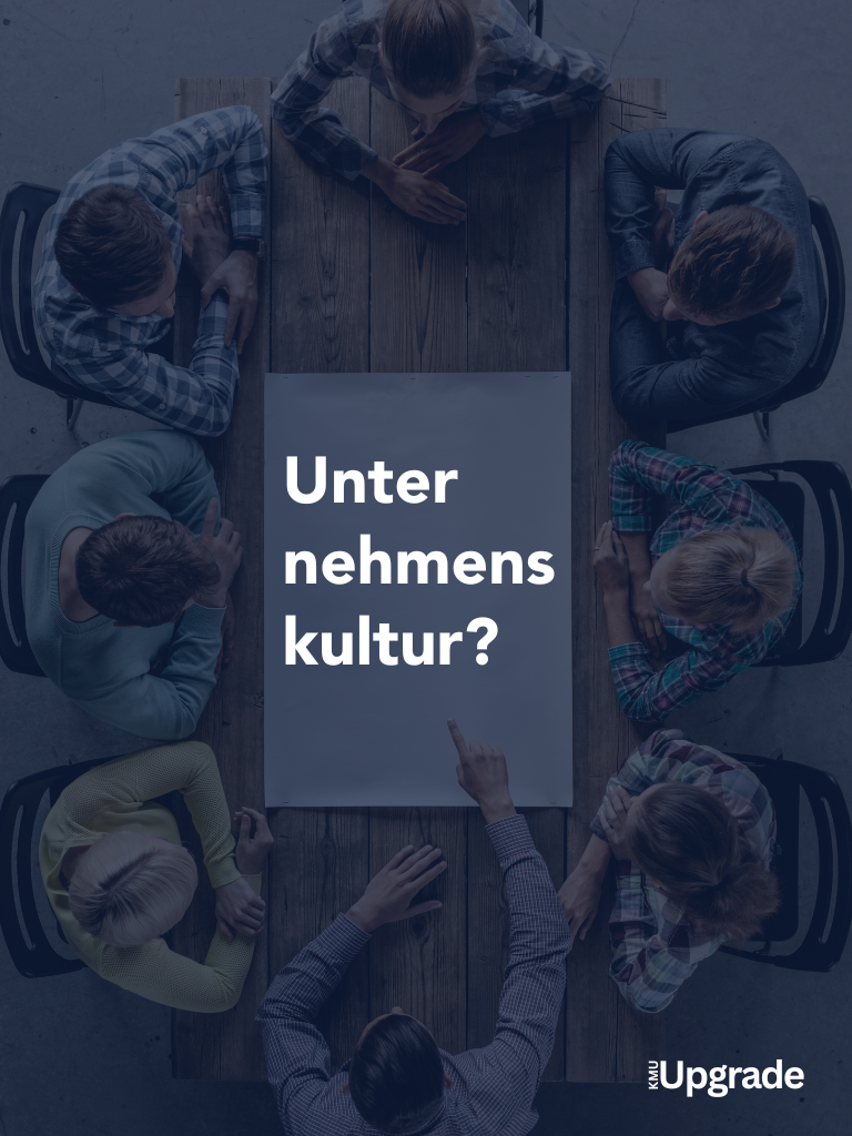 Teammeeting aus der Vogelperspektive mit Fokus auf das Thema Unternehmenskultur. Mitarbeitende diskutieren an einem Holztisch, zentrale Frage: ‚Unternehmenskultur?‘. KMU Upgrade Branding unten rechts.