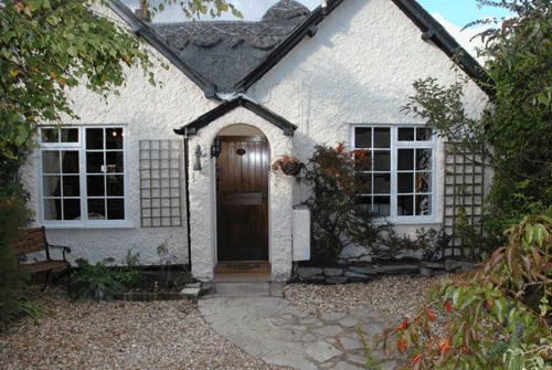 outside front aspect of accommodation, double-fronted windows, arched entrance doorway