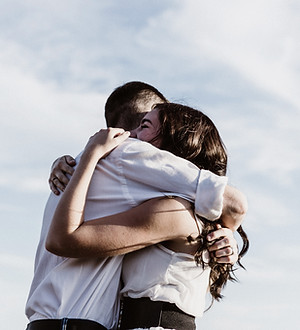Couple embracing each other against a bright sky, WRITE, loving embrace in the open air