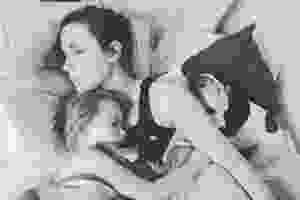 A black and white photo of Bella asleep in bed, on one side is a small child, and on the other a little terrier type dog. Both are also asleep.