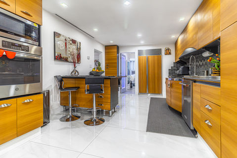 Real estate photo of an open kitchen and dining area with bar seating and bright interior lighting.