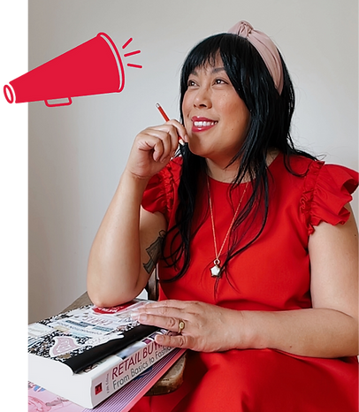 hris Guillot is seated and holding a pencil. A composition notebook, textbook, and folder are stacked on the desktop. Her dress has ruffled sleeves and she wears a knotted hair band. The photo is accented with a megaphone icon.