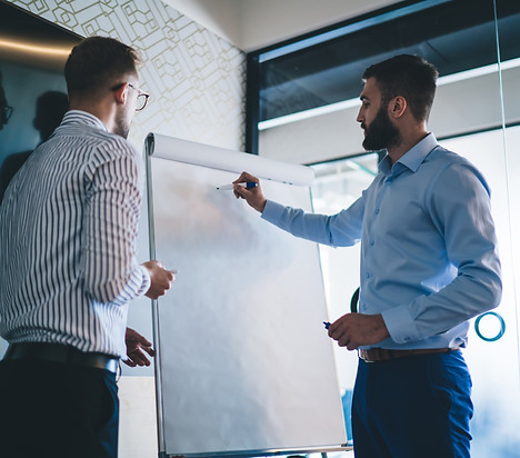 Two business men strategizing on a white board