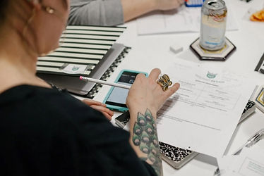 Business owner completing a course worksheet. She uses a calculator and pencil to solve profit-related math problems.